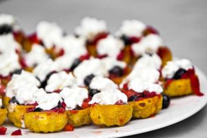 Small roasted potatoes topped with whipped cream on a white serving platter.