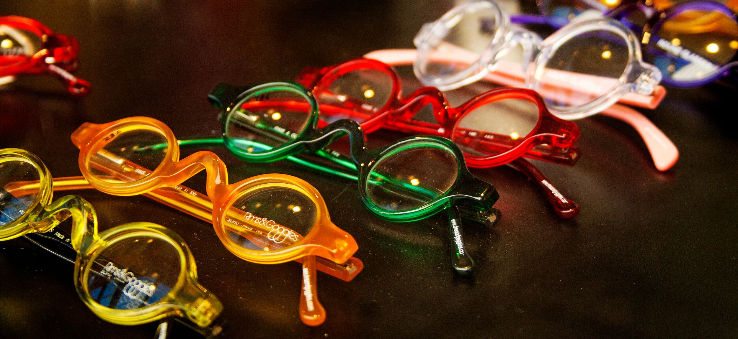 Colorful eyeglass frames arranged in a row displaying various vibrant hues.