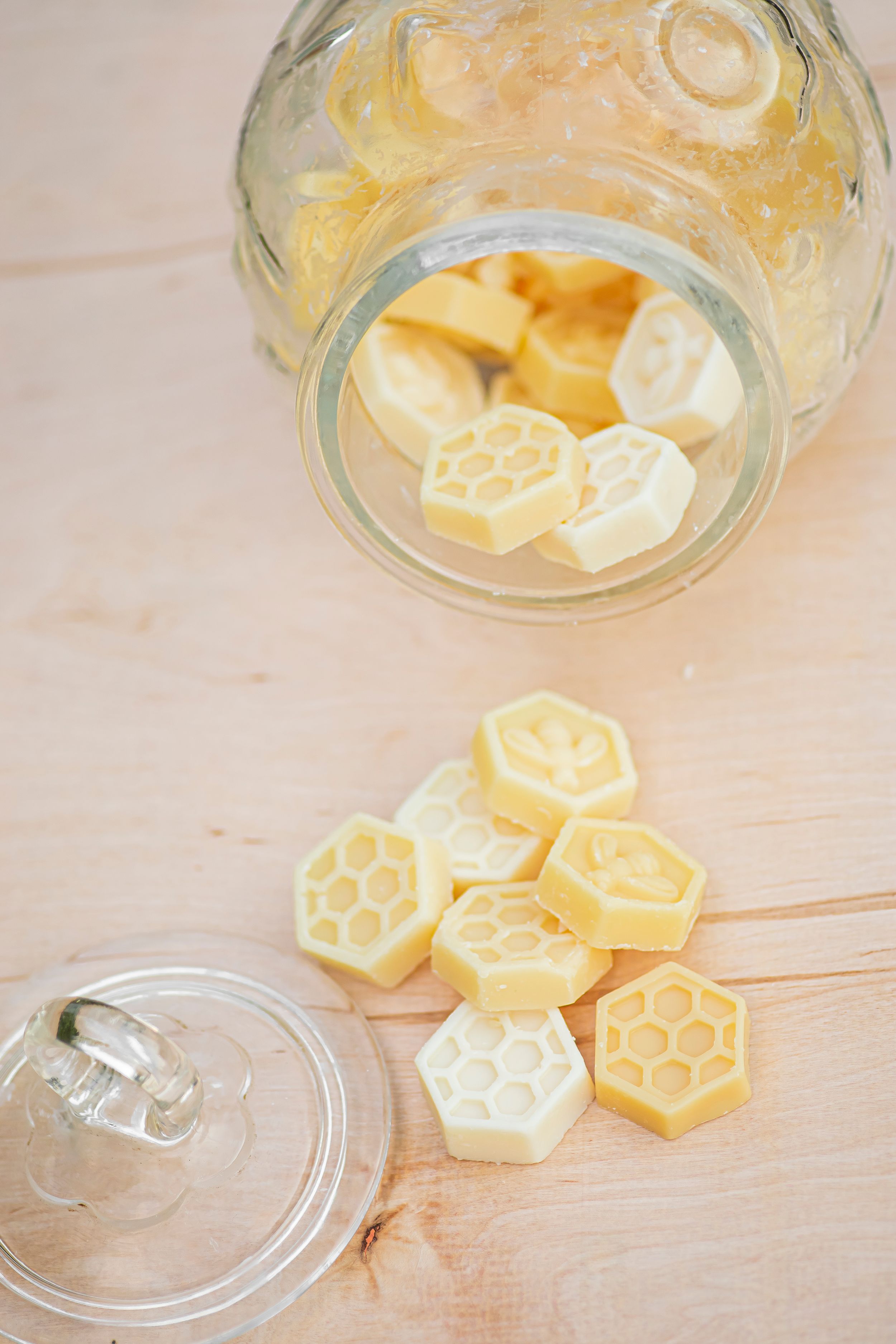 Hexagonal honey-colored hard candle melts scattered near a glass jar lid on a light surface.
