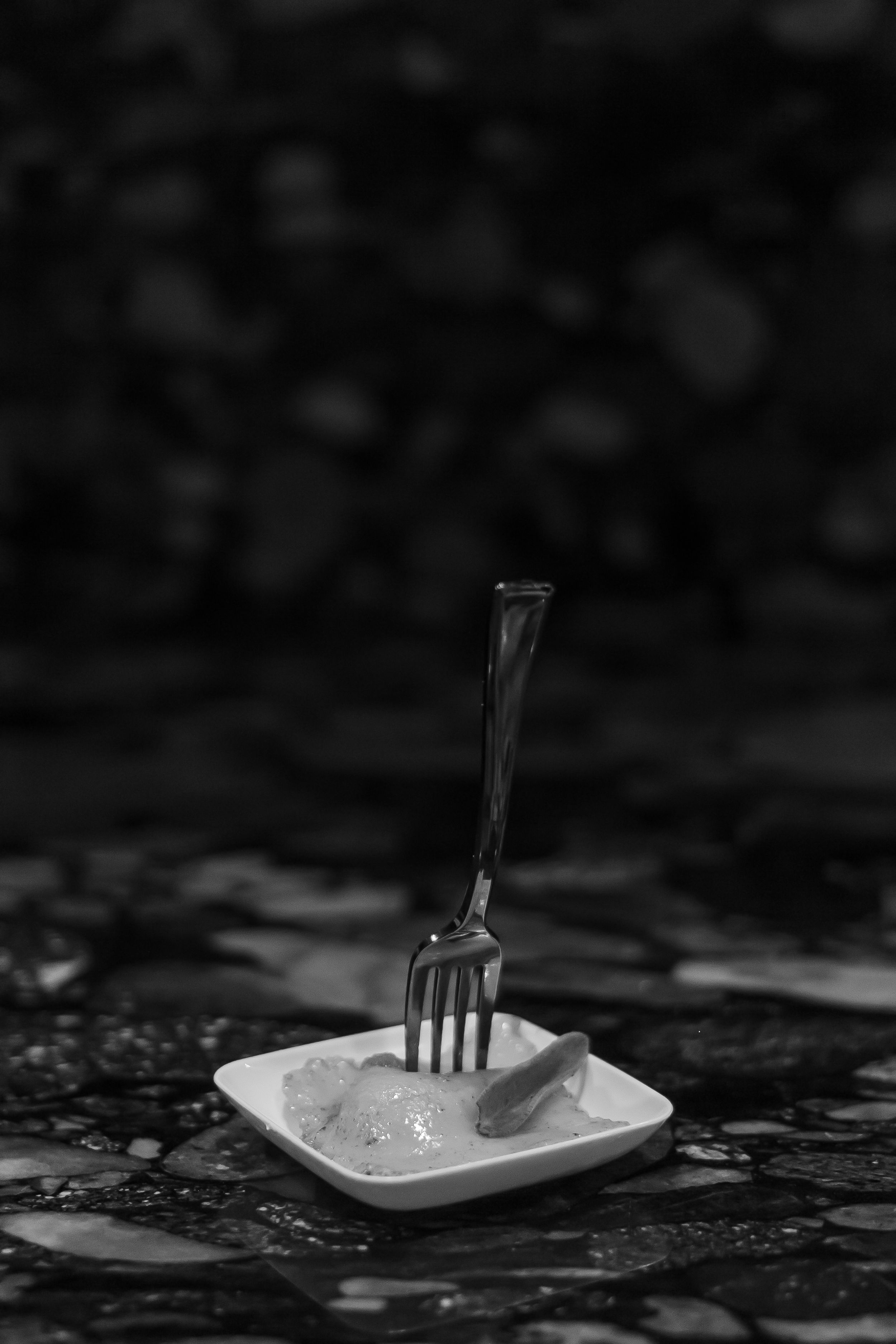 Black and white artistic photo of a fork on small square plate.