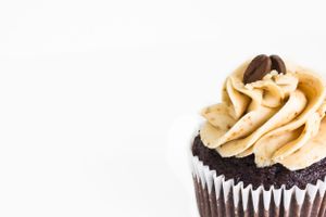 Chocolate cupcake with swirled peanut butter frosting against white background.