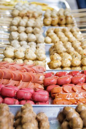 Colorful array of sausages and meatballs displayed at a food market.