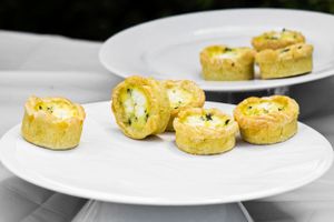 Mini quiche appetizers arranged on white plates.
