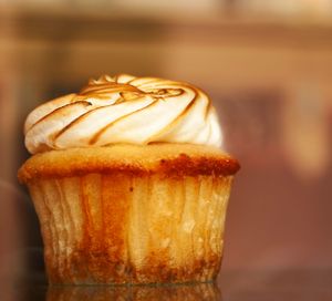 Close-up of a vanilla cupcake with swirled white frosting and caramelized drizzle.
