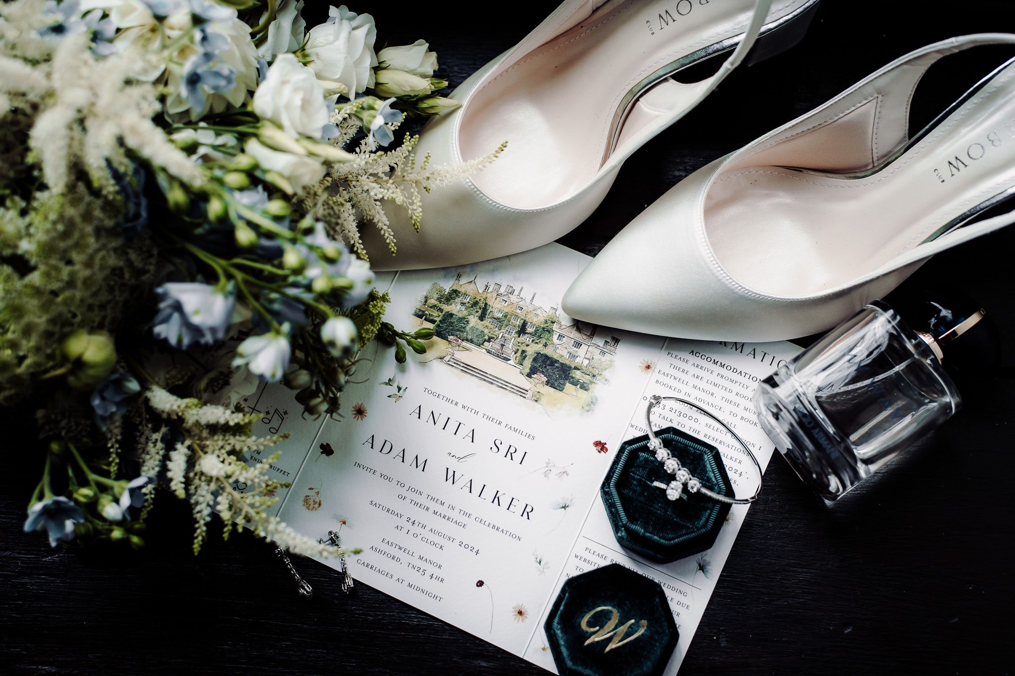 Wedding invitation details with white flowers and champagne bottle.