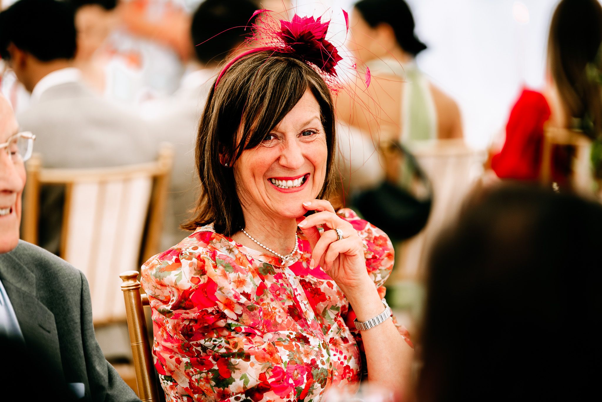 Guests enjoying a lively celebration in formal attire with bright red floral accents.