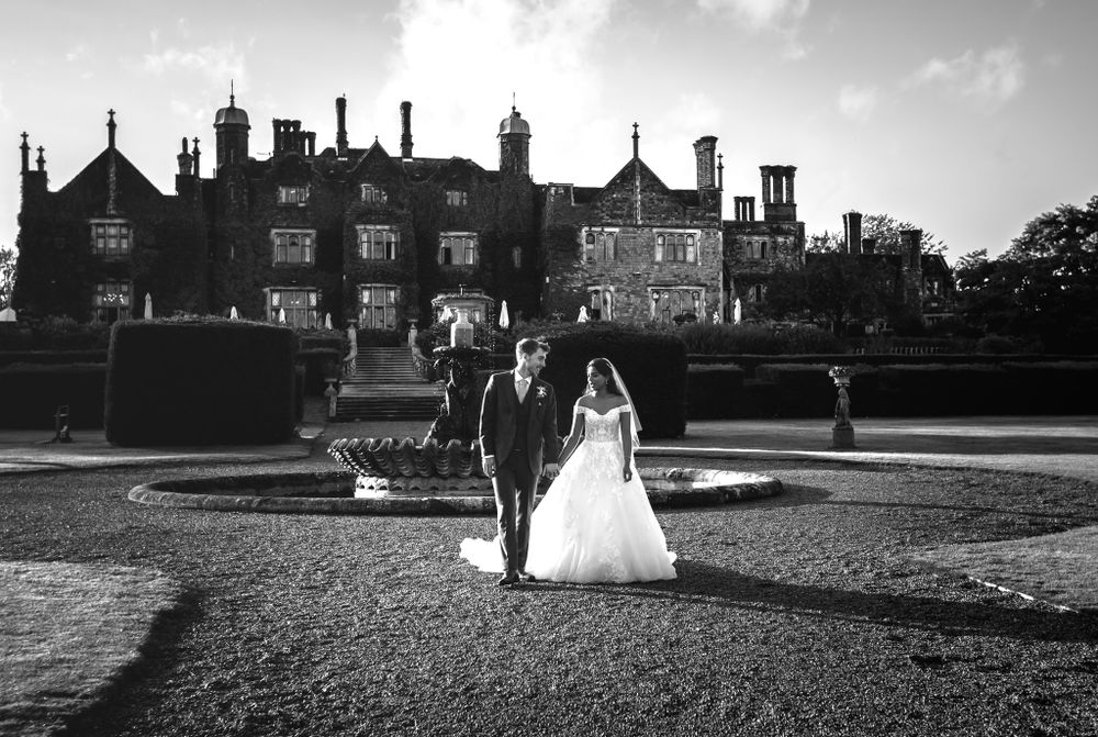 Black and white panoramic view of a grand estate building with wedding couple in the distance.
