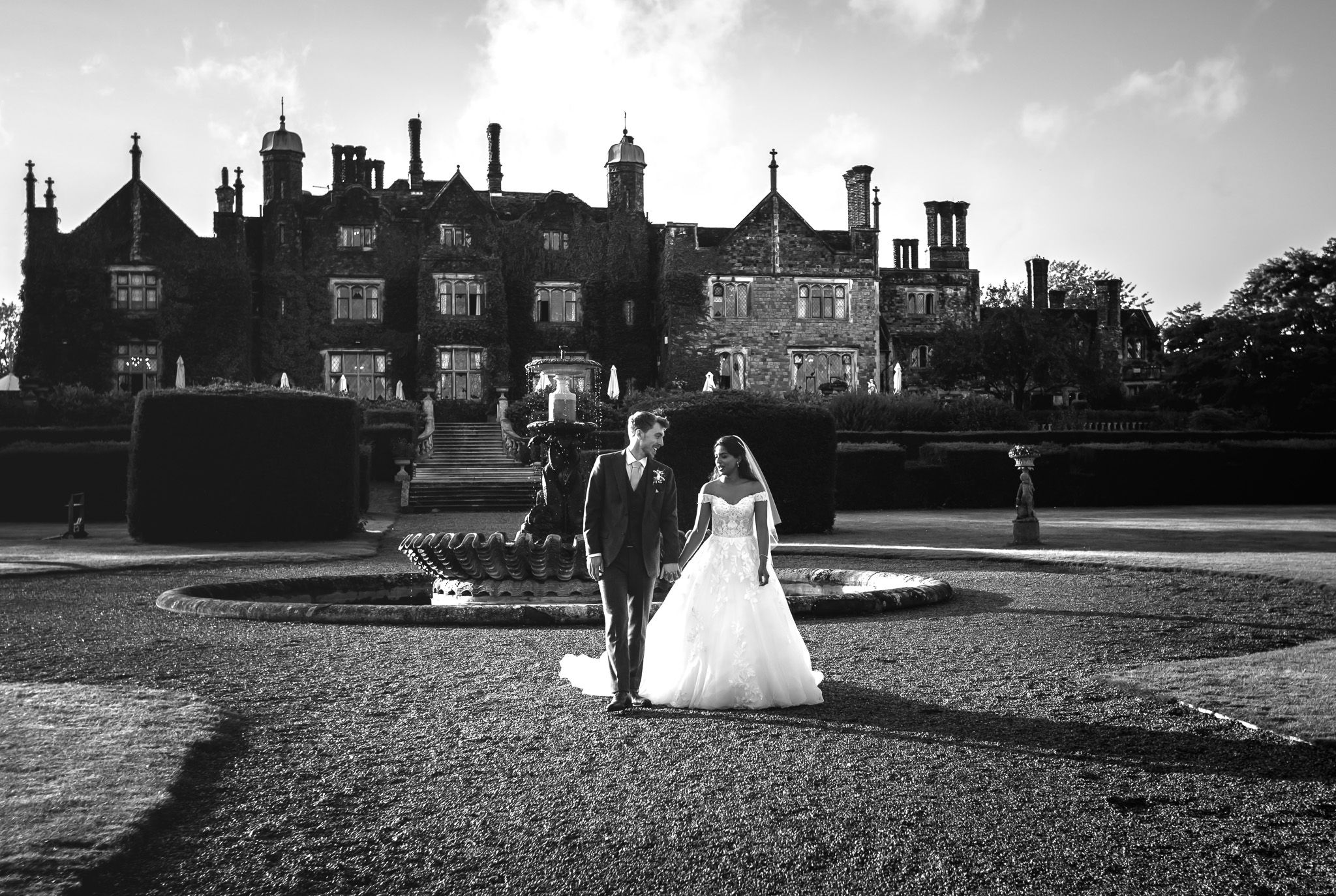 Black and white panoramic view of a grand estate building with wedding couple in the distance.