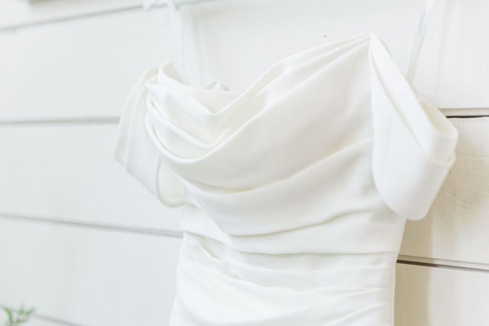 Close-up detail of a white wedding dress bodice with ruched fabric design.