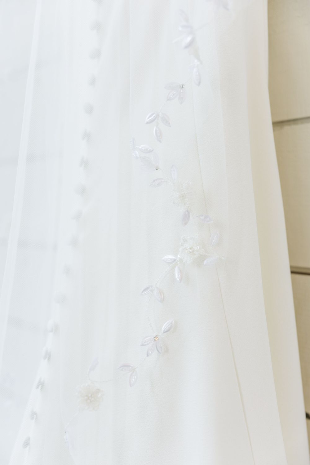 Delicate floral embroidery detail on white wedding dress fabric.