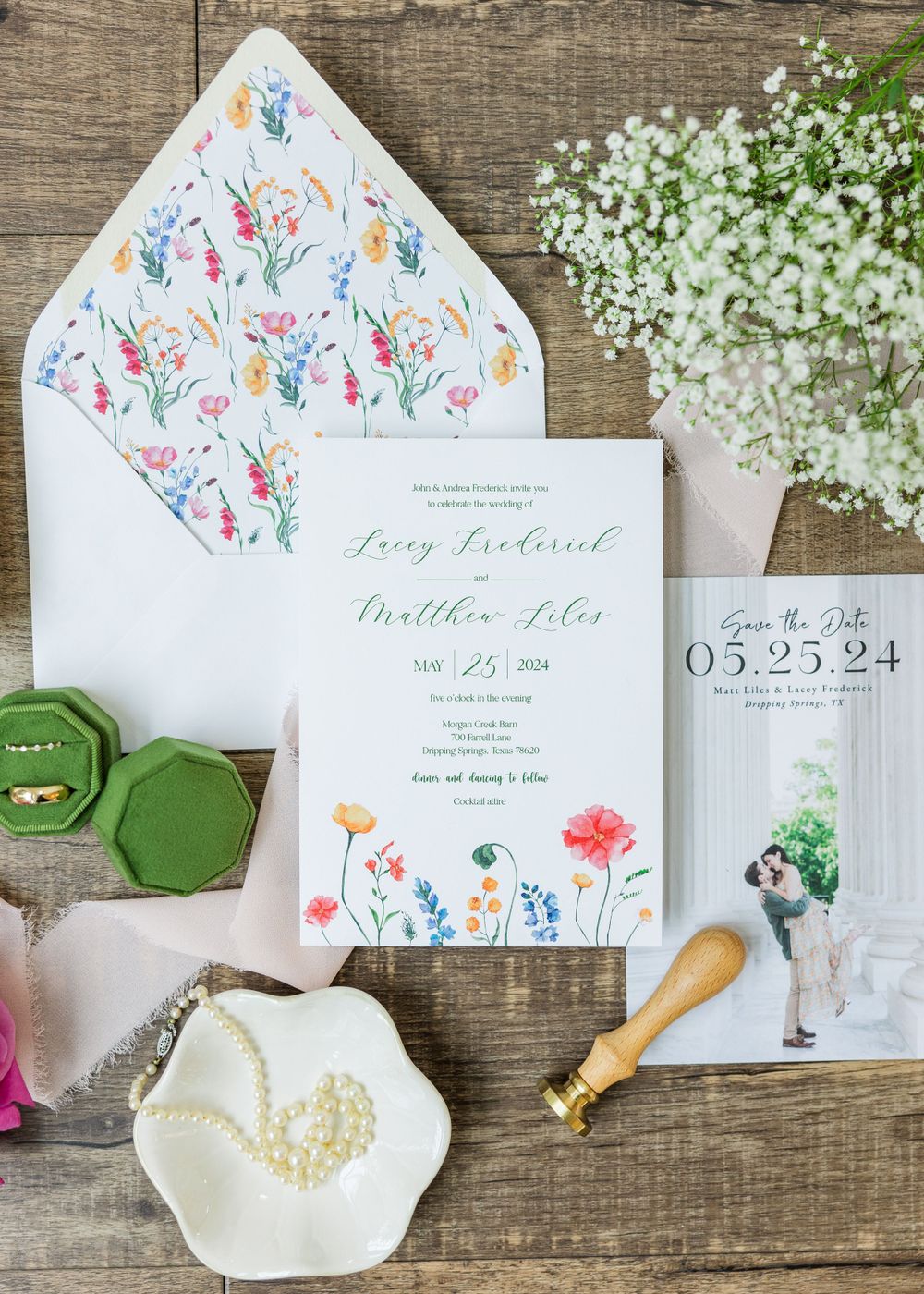 Wedding invitation suite with floral patterns and green wax seals on wooden background.