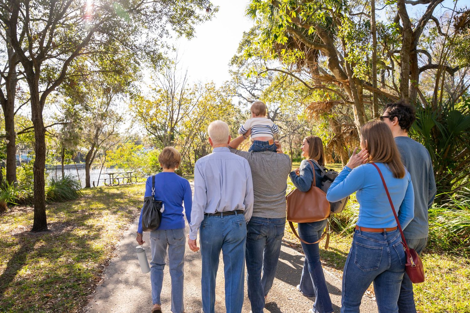Group of people walking together on a tree-lined path during a sunny autumn day.
