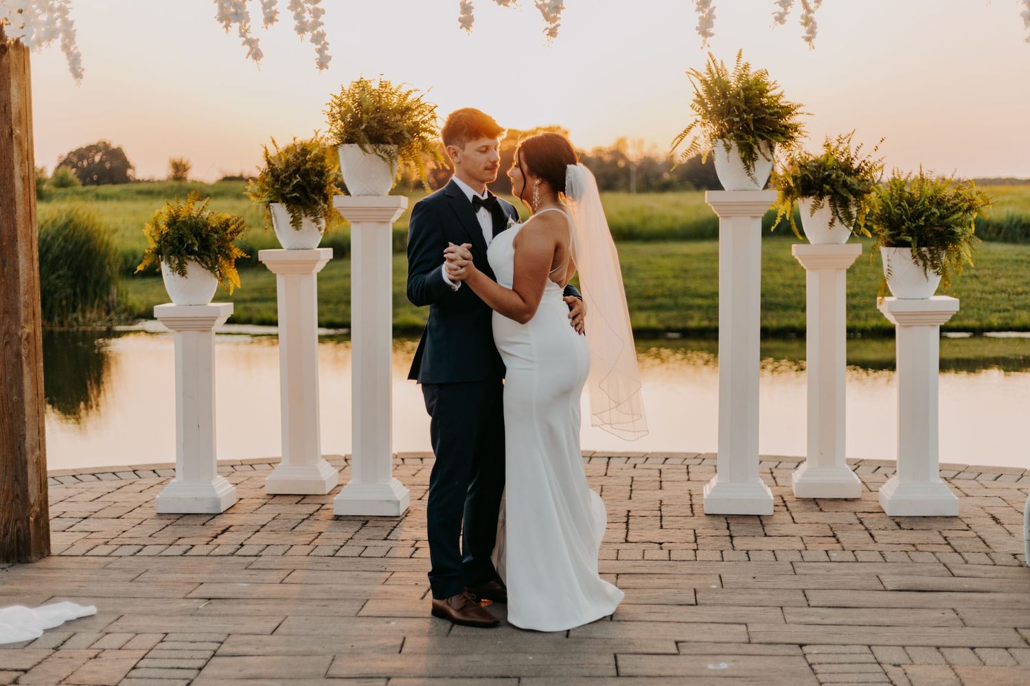 A wedding couple shares their first dance at sunset with sunflower decorations.