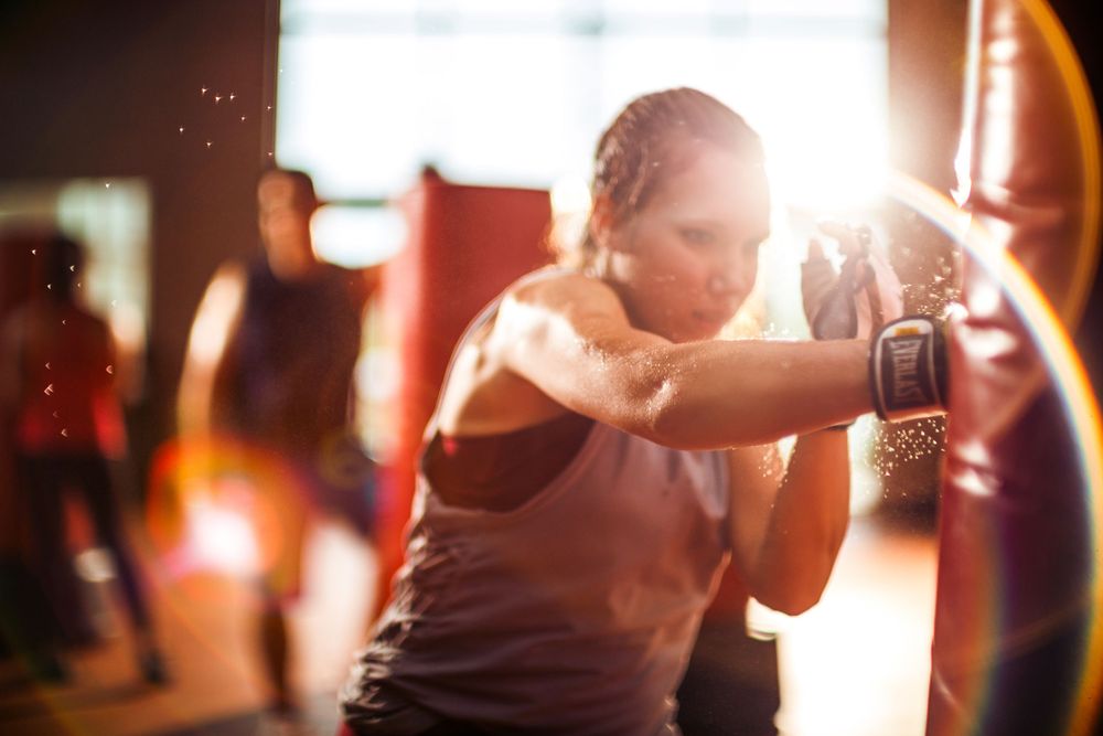 Person practicing boxing moves on a punching bag in dramatic lighting.