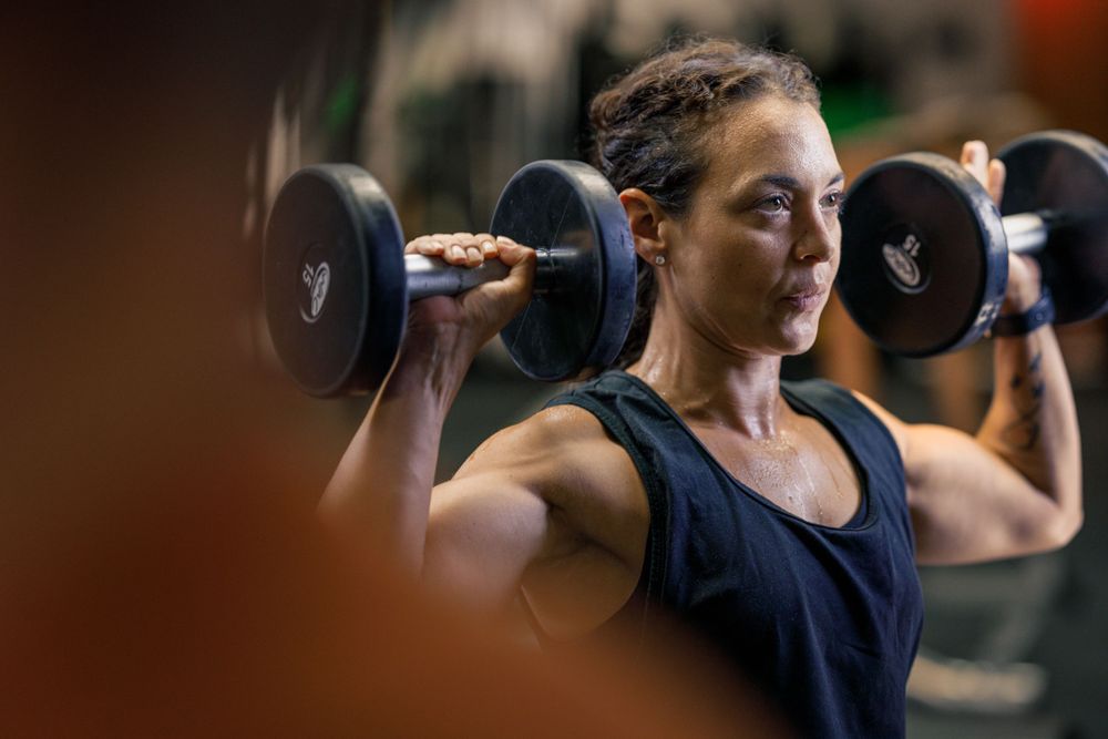 Athletic person lifting heavy dumbbells during an intense workout session.