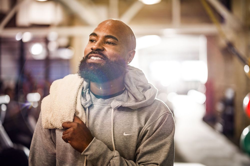 Person in gray hoodie smiling during workout at fitness center.