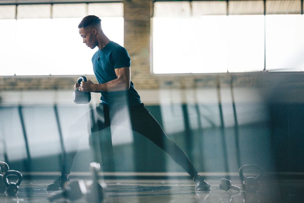 Person in teal shirt running on indoor track with motion blur effect.