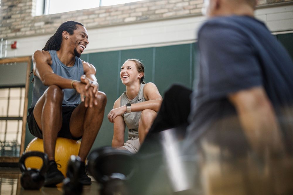Fitness enthusiasts sharing a laugh during break at gym workout session.