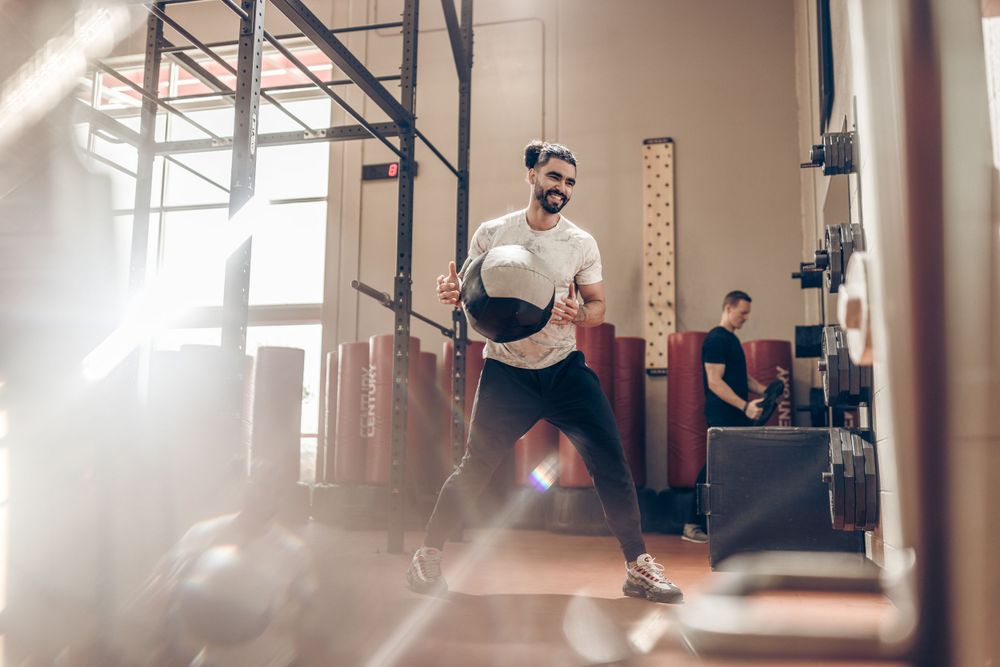 Athlete performing dynamic exercise in sunlit indoor training facility.