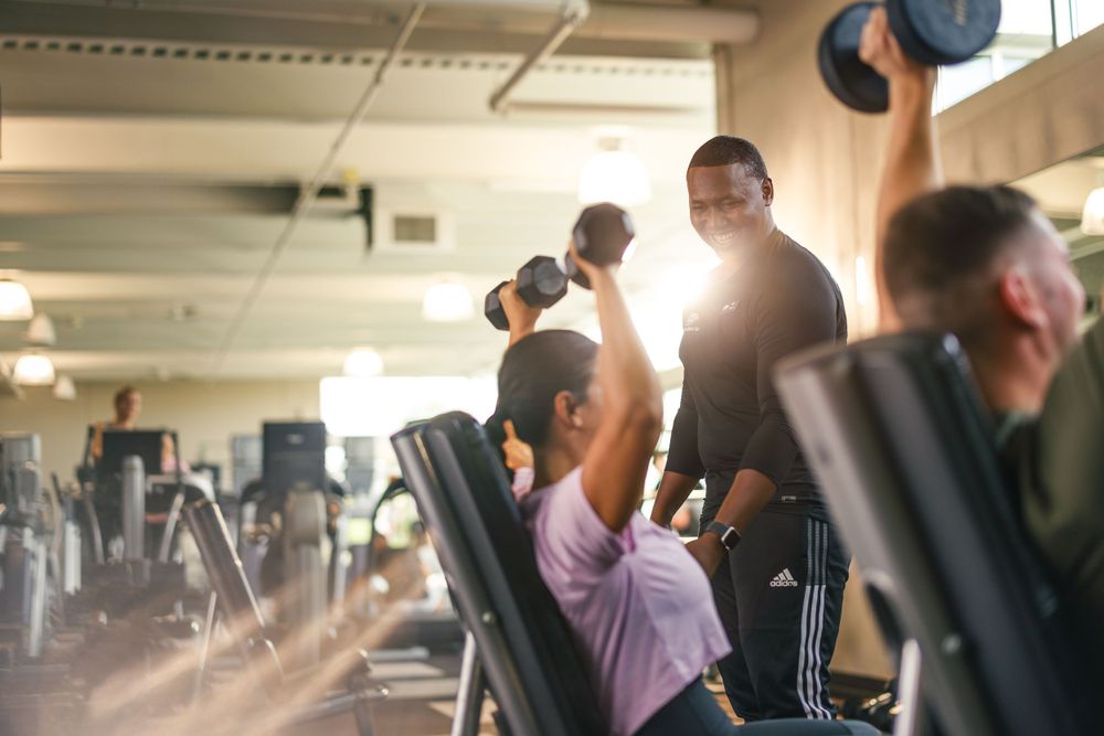 Fitness enthusiasts working out with weights in well-equipped gym environment.
