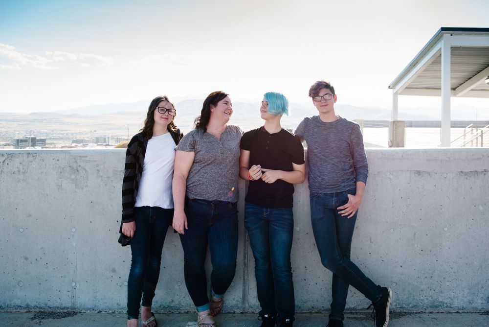 Group of friends leaning against concrete wall with ocean view.