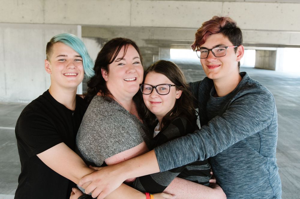 Friends hugging and laughing together in parking structure.