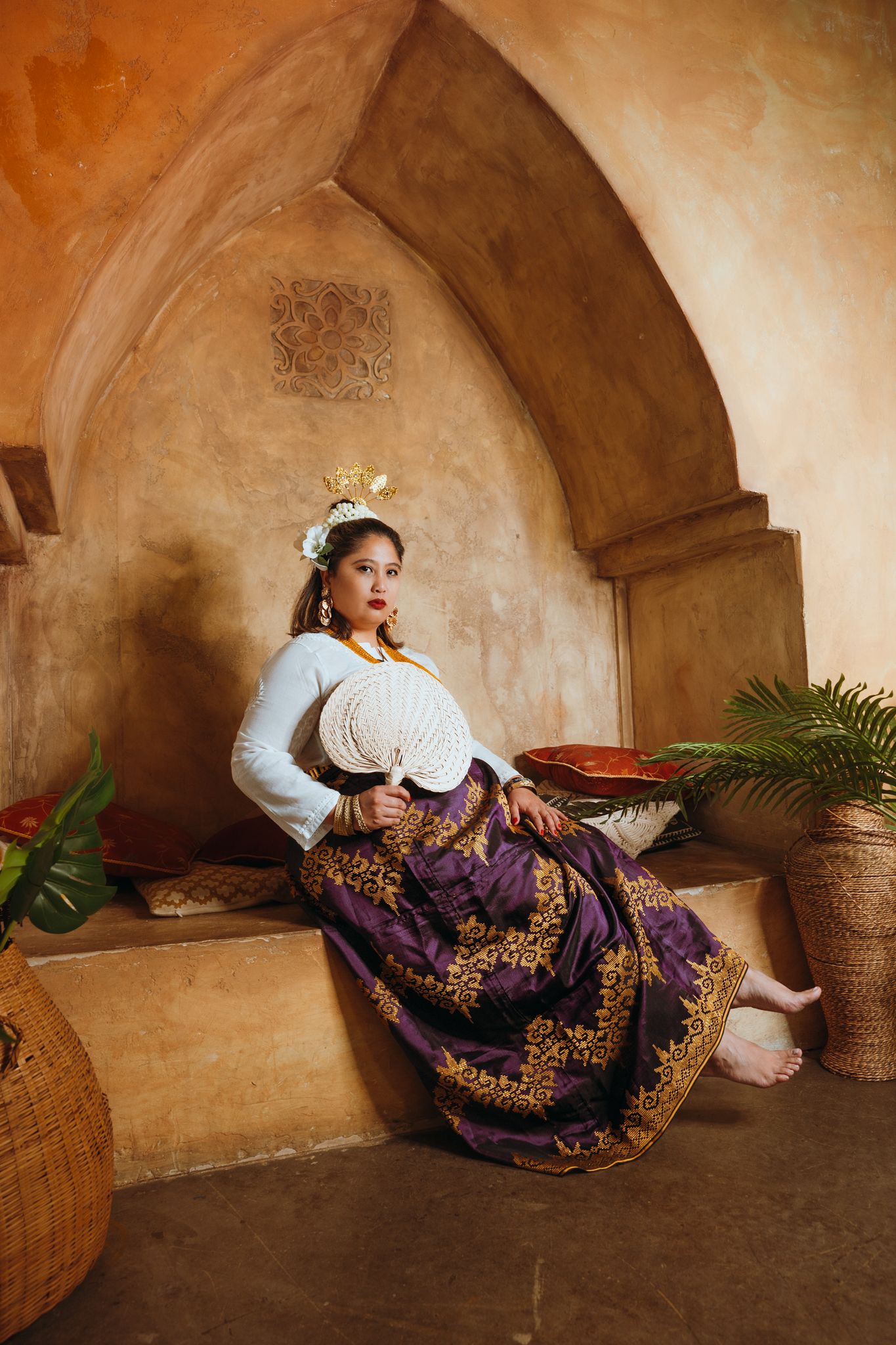 Traditional fashion portrait in arched alcove with ornate skirt and white blouse.