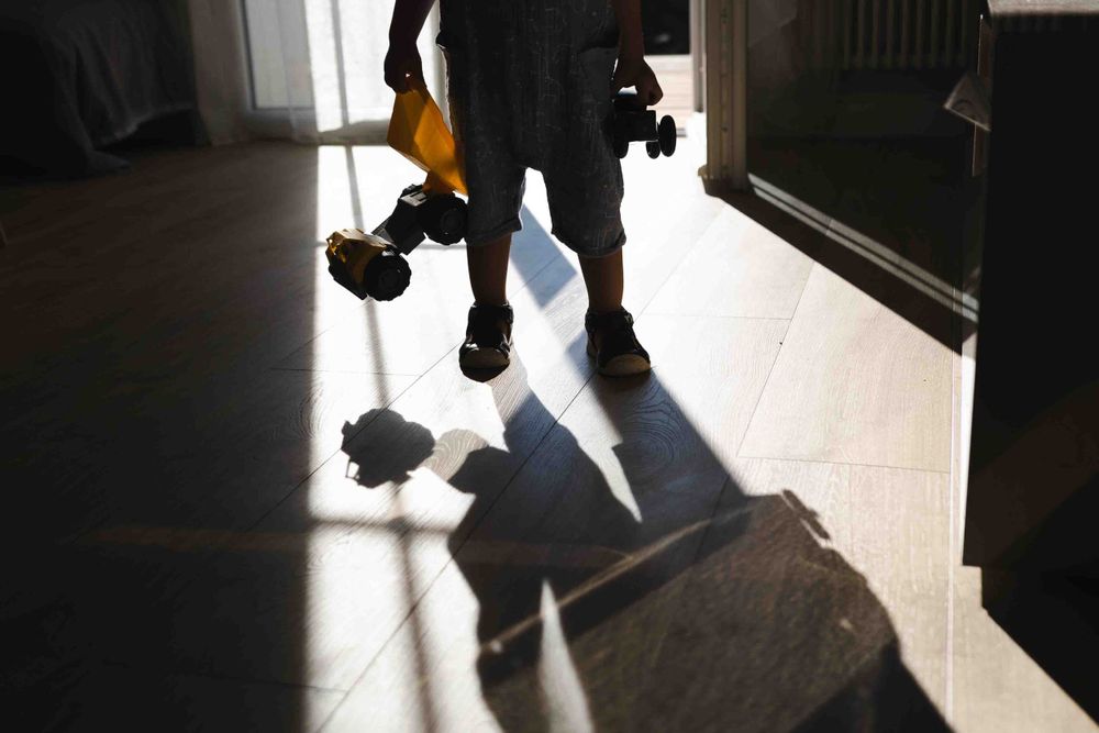 Dramatic shadow cast on floor from silhouette standing in doorway with camera equipment and gear.