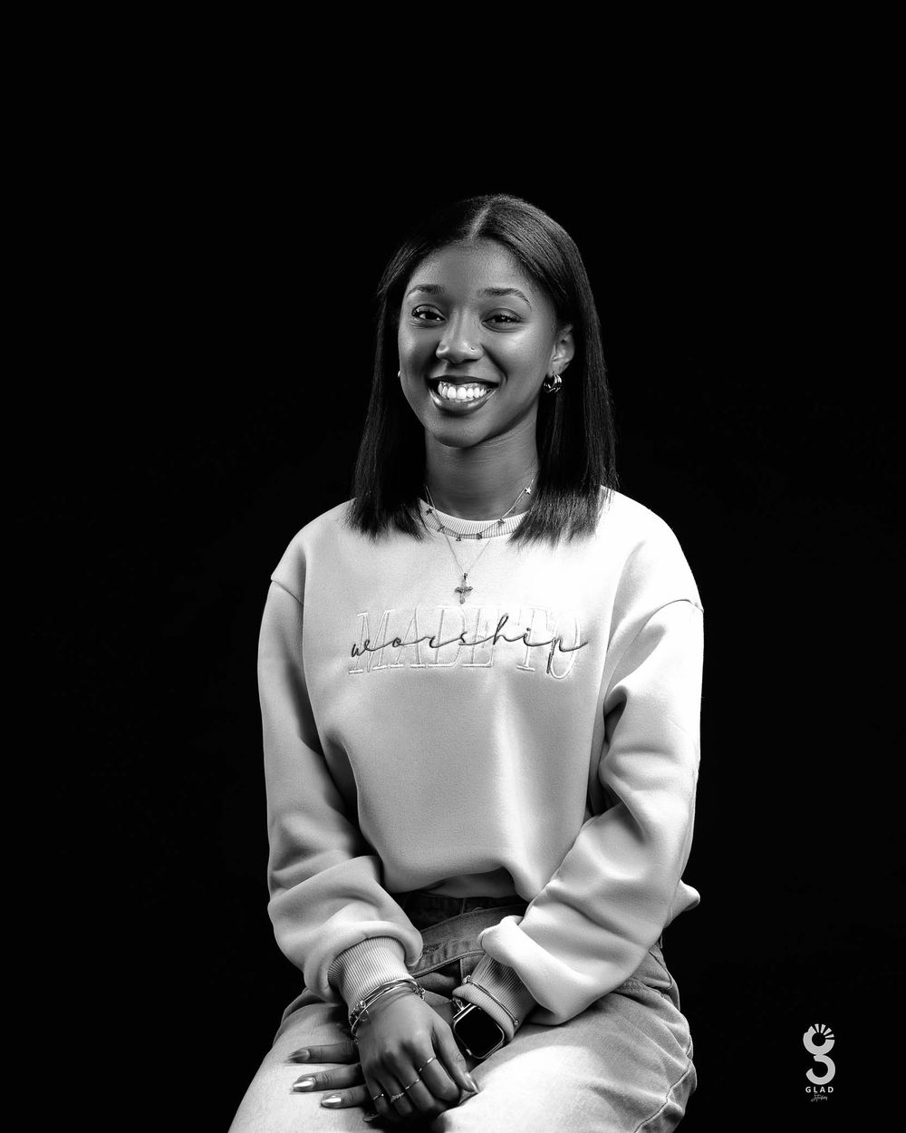 A person wearing a white sweatshirt poses against a black background in a series of candid expressions.