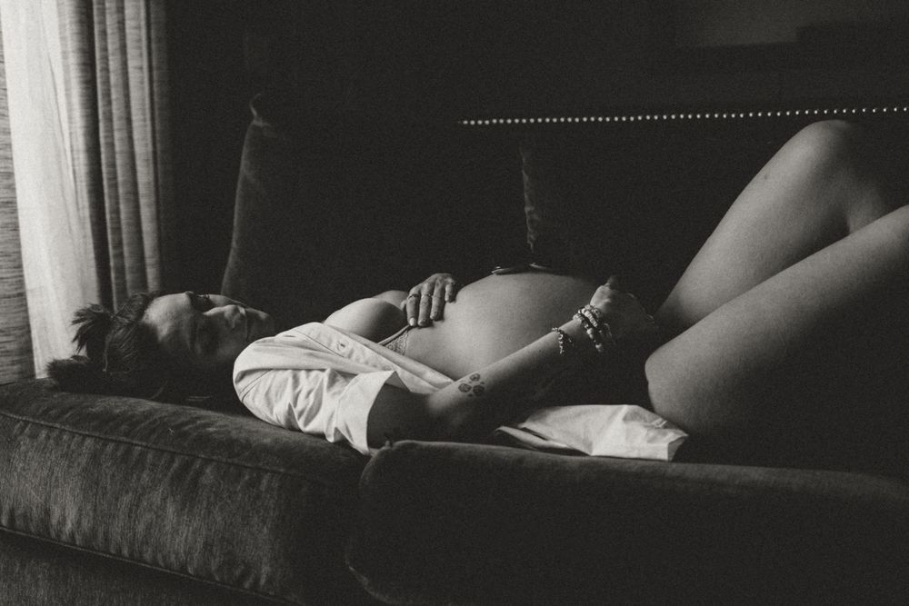 A vintage black and white photograph shows a resting figure lounging on a couch in casual attire.