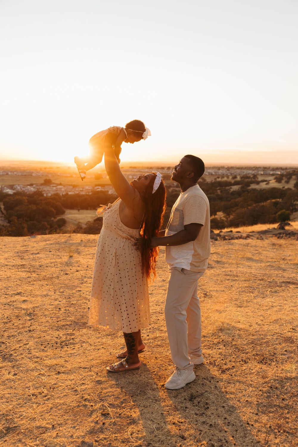 Family enjoying a beautiful sunset moment on a hill, silhouetted against the golden evening sky.