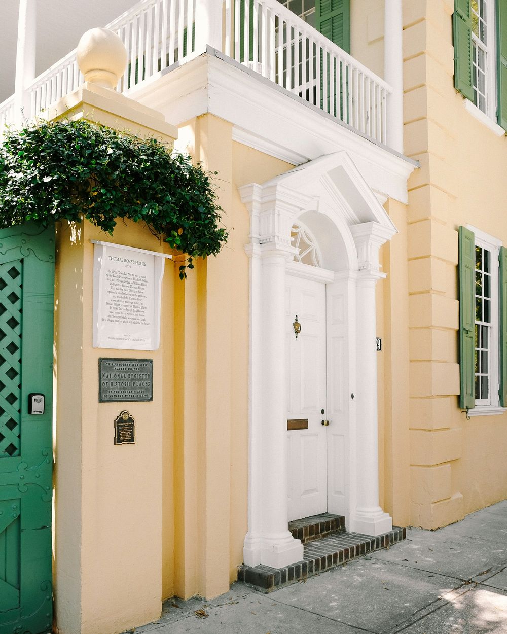 A historic building facade with three ornate doorways painted in green and white with yellow walls.