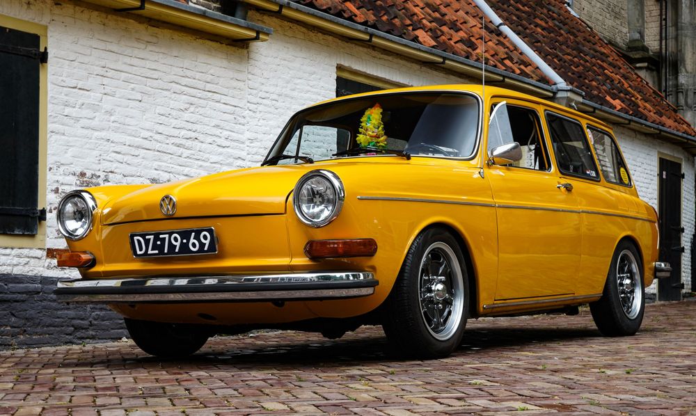 Knalgele oldtimer geparkeerd in een schattig straatje – retro vibes!