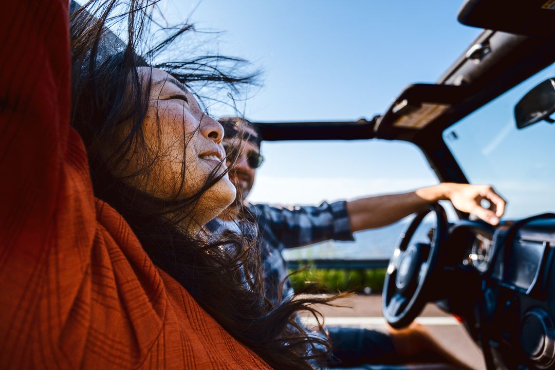 People enjoying a convertible ride with wind in their hair on a sunny day.