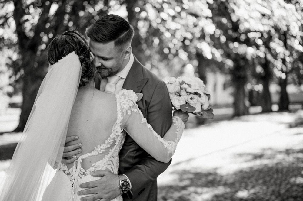 Black and white photo capturing an intimate moment between newlyweds in a garden setting.