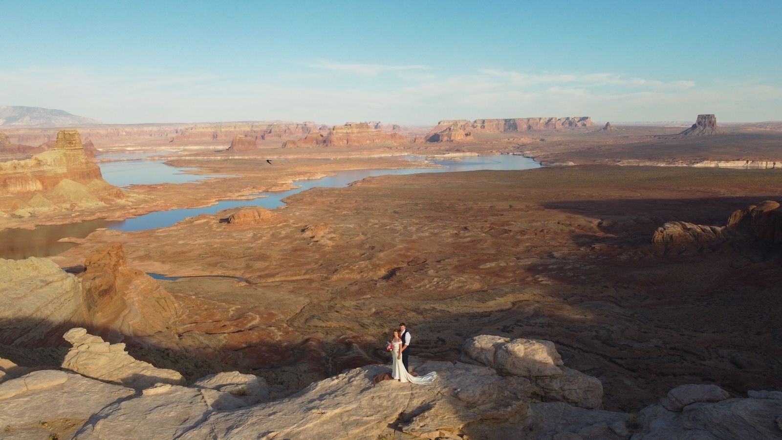 A panoramic view of Lake Powell's winding shoreline and red rock cliffs stretches across the desert landscape.