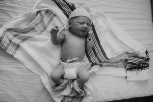 A series of black and white photos showing a newborn baby sleeping swaddled in blankets.