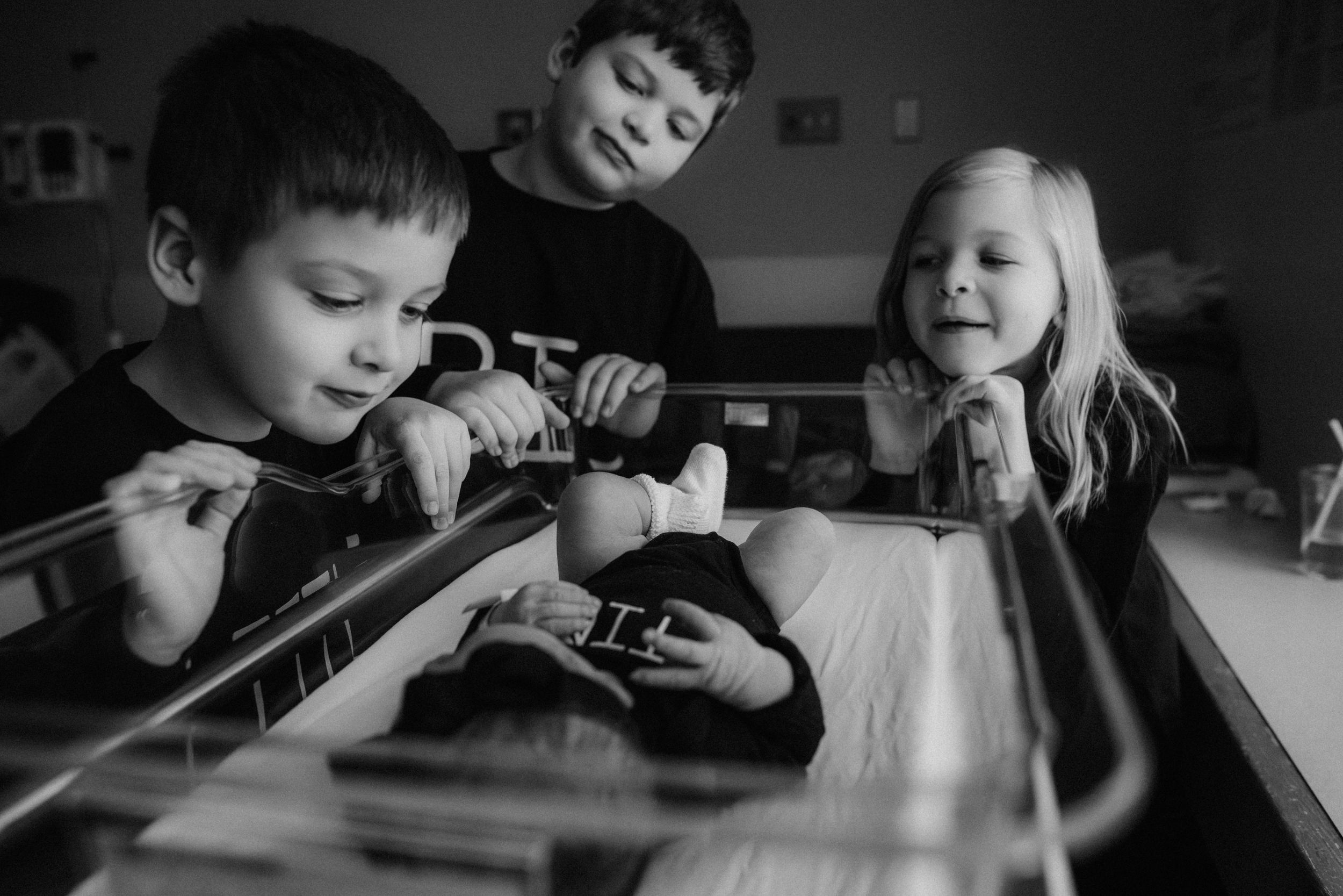 Siblings admiring newborn in bassinet for Fresh 48 photography session captured by Maryland Fresh 48 newborn photographer Mallory Bramlett.