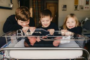 Siblings looking at newborn in bassinet for Fresh 48 photography session captured by Maryland Fresh 48 newborn photographer Mallory Bramlett