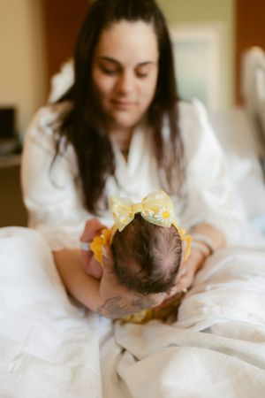 A tender moment captured as parent and baby share quiet time together in soft white bedding.