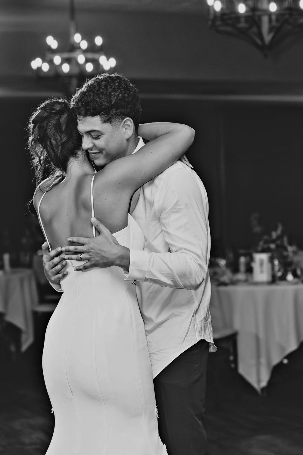Black and white photo of a couple sharing their first dance at a wedding reception.