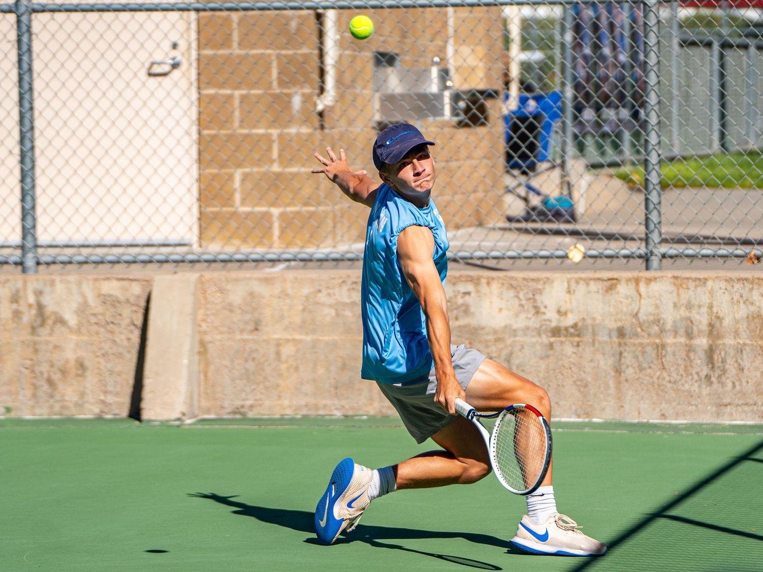 Tennis player prepares to serve on outdoor court during sunny day.