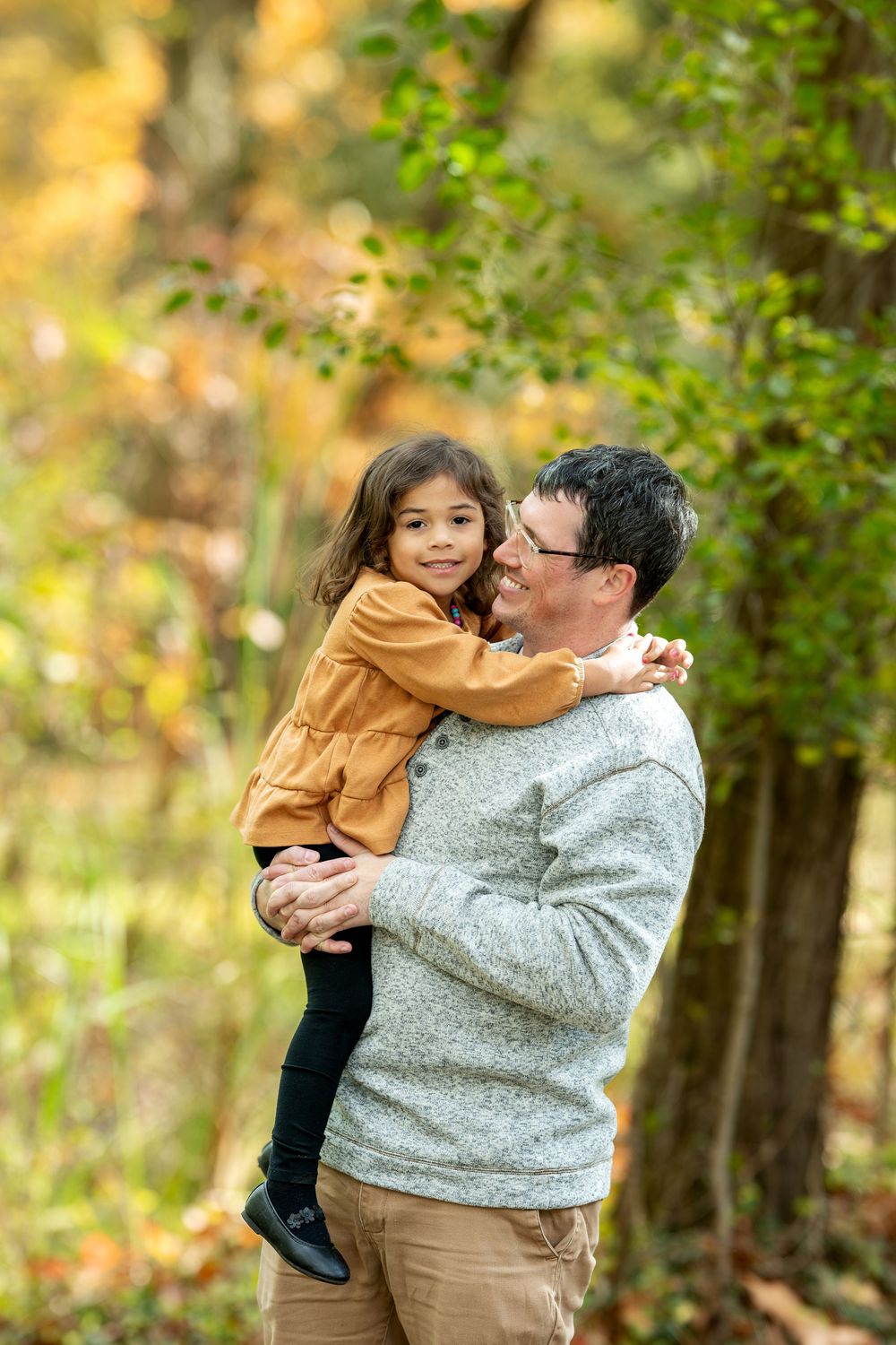 Loving father and young daughter sharing a joyful moment in a golden autumn park.