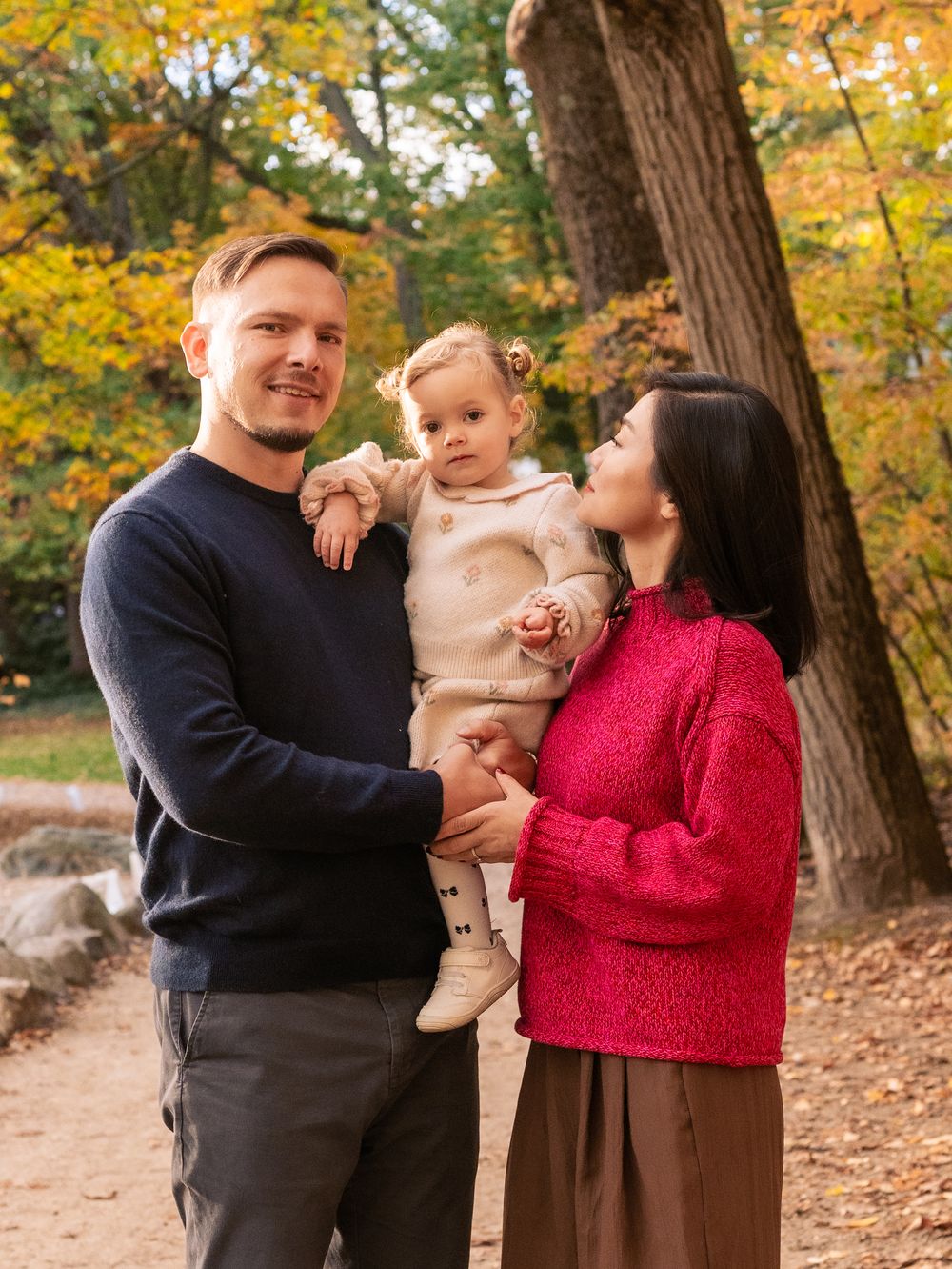 Family shares joyful moments together during autumn photoshoot in a park with golden fall foliage at Menotomy Rocks Park in Arlington, MA.