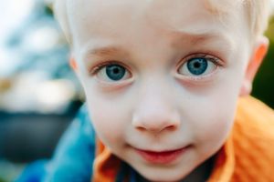 Close up of bright blue eyes and sweet smile on a young child's face.
