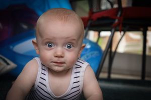 Close-up view of an infant in a striped outfit with bright blue eyes.