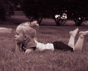 Baby lying on grass in a sepia-toned photograph.