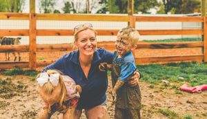 Family and pets playing outdoors near a rustic wooden fence.