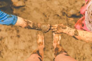 Muddy footprints and handprints visible in wet soil or clay.