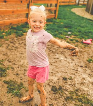 Kids having fun jumping and playing in wet mud during outdoor playtime.